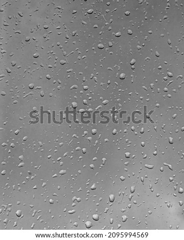 Rain drops on window glasses surface with gray sky background. Natural backdrop of raindrops. Abstract overlay for design. The concept of bad rainy weather.