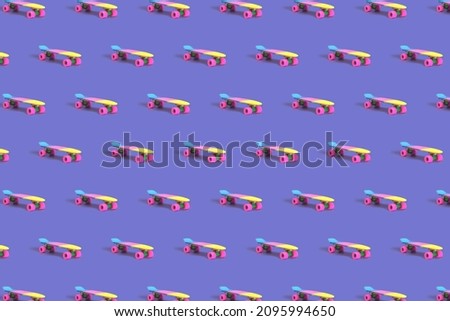 Pattern made of pastel neon rainbow colored Penny board skateboard on solid purple background. Plastic mini cruiser. Youth minimalistic Sport inspired summer fun concept. 2022 color trend