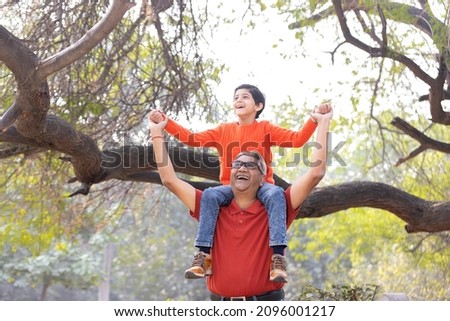 Happy grandfather carrying grandson on shoulders at park
 Royalty-Free Stock Photo #2096001217