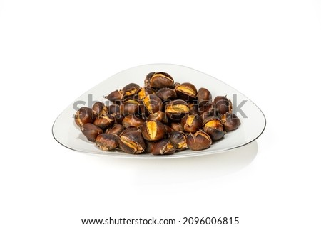 Cooked Chestnuts. Baked chestnuts in a white plate, clean, with white background, close-up, triangular plate, roasted Royalty-Free Stock Photo #2096006815