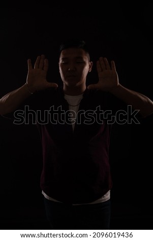 Asian man dancing to music in the dark