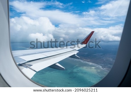 Classic image through aircraft window onto wing. Flight view over sea in cloudy weather.