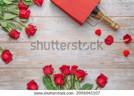 A bottle of sparkling wine in a package, heart-shape decoration, luxury roses, a wooden surface. Valentine's Day 14 february, Engagement, wedding anniversary, romantic evening  preparation