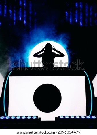 Pretty young disc jockey girl  mixing music and dancing. on colorful display background