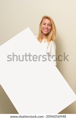 blonde young woman exposing blank pictures on the wall furniture and floor