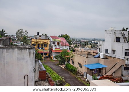 Roof top view of residential group housing , apartment and bungalows in the urban area, picture captured during rainy season with dark clouds. Parked vehicles outside of the houses at Kolhapur, India.