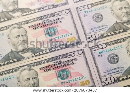 Fifty dollar bills are spread out on the surface. Horizontal photo