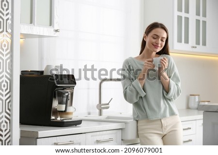 Young woman enjoying fresh aromatic coffee near modern machine in kitchen Royalty-Free Stock Photo #2096079001
