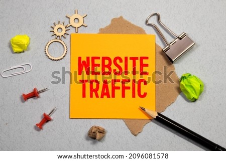 Closeup on businessman holding a card with WEBSITE TRAFFIC rising arrow and chart, business concept image with soft focus background