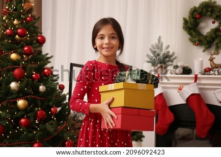 Cute child with gift boxes near Christmas tree at home