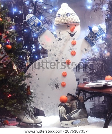 a snowman figurine in a hat and gloves. hands are raised up . smile.