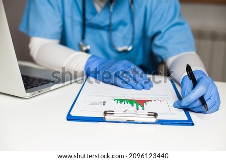 Epidemiologist in office analyzing COVID-19 infection rate chart,Coronavirus disease statistics,update on new daily cases and deaths worldwide,preventive and protective pandemic measures and rules Royalty-Free Stock Photo #2096123440