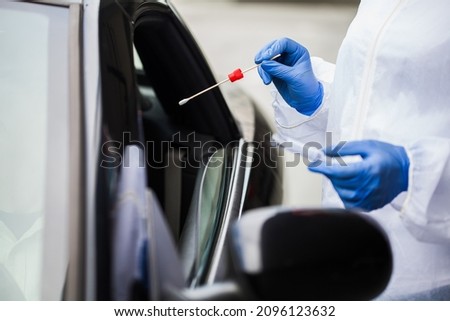 Closeup of medical worker's hands in gloves performing drive thru swab sample collection,driver in car in mobile testing center getting health check through vehicle window,Coronavirus PCR test process Royalty-Free Stock Photo #2096123632