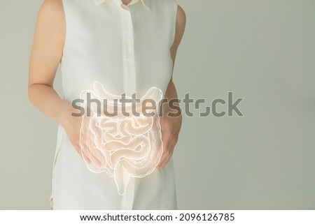 Unrecognizable female patient in white clothes, highlighted handrawn intestine in hands. Human digestive system issues concept. Royalty-Free Stock Photo #2096126785