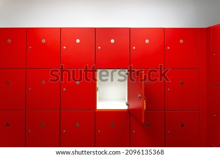 Deposit red locker boxes or gym lockers inside of a room with one central opened door Royalty-Free Stock Photo #2096135368