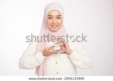 Beautiful hijab woman, cosmetics and skincare concept - happy muslim young woman holding jar of cream over white background Royalty-Free Stock Photo #2096135800