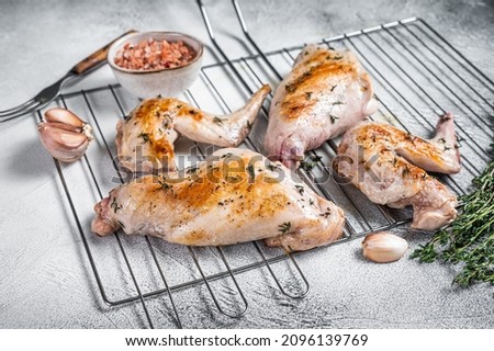 Baked rabbit legs on a grill with thyme. White background. Top view