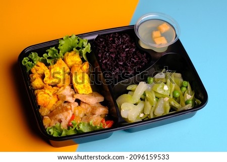 bento sehat. bento diet. black rice, yellow tofu, savory chicken, stir-fried pumpkin and chickpeas, and fruit pudding. healthy food balanced nutrition for optimal growth and development. catering. 