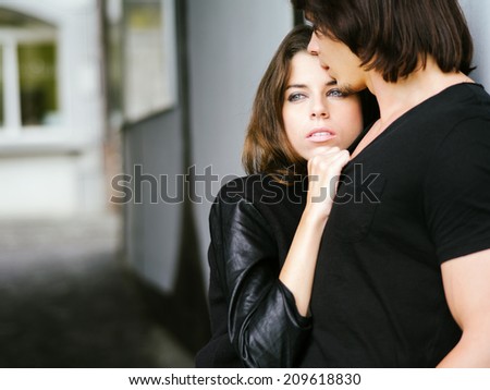Photo of a young couple in love holding each other in an alley.