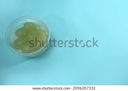 Picture of homemade white or green grapes pudding in a plastic cup, with blank space for text, body copy, body text, or headline.