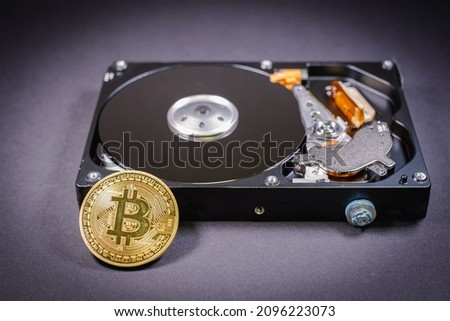 one bitcoin coin lies on a screwed hard drive