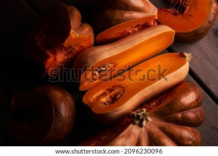 Two different sliced ripe orange pumpkins closeup wooden background