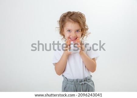 a little cute girl holds  pours water into a glass isolated on a white background.  little girl  holding glass of pure clean mineral water, recommending healthy lifestyle, everyday ha