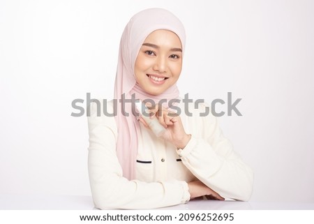 Hijab woman holds bottle with serum for skin care. Photo of asian muslim woman after shower on white background. Beauty and skin care concept Royalty-Free Stock Photo #2096252695