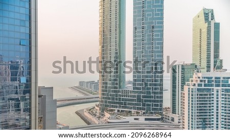 Promenade and Dubai cityscape seen from Dubai marina timelapse. Aerial view to JBR district and Bluewaters Island behind with hotels and skyscrapers.