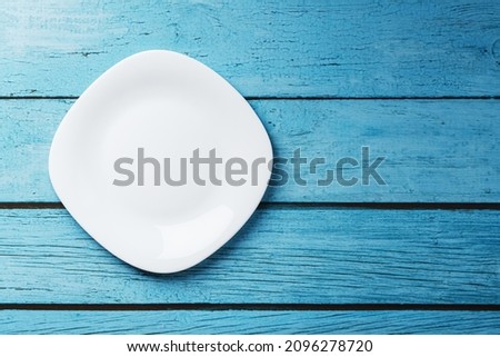 Empty round bowl on a blue wooden background from above. Free space