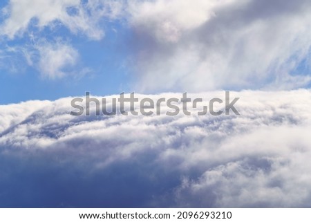 Background of high clouds covering the mountain and blue sky above the clouds.