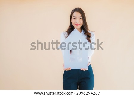 Portrait beautiful young asian business woman show home sign and banner on isolated color background