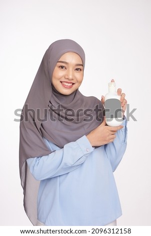 Hijab woman hold white bottle shampoo and conditioner. Happy muslim hijab young woman with balm bottle applying hair mask. Hemp, Cbd cosmetic product. Royalty-Free Stock Photo #2096312158
