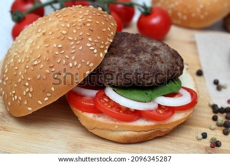 Grilled burger cooked with your own hands with tomatoes onions and herbs lies on a wooden board