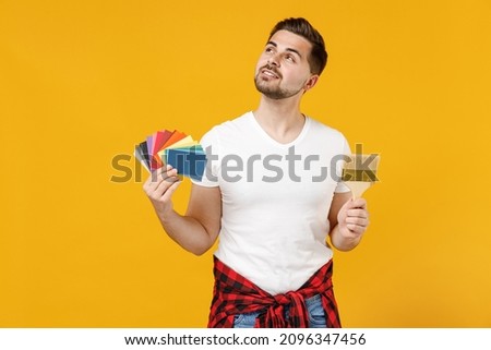 Young fun employee handyman man in t-shirt hold color palette paint brush look overhead isolated on yellow background studio. Instruments accessories for renovation apartment room Repair home concept