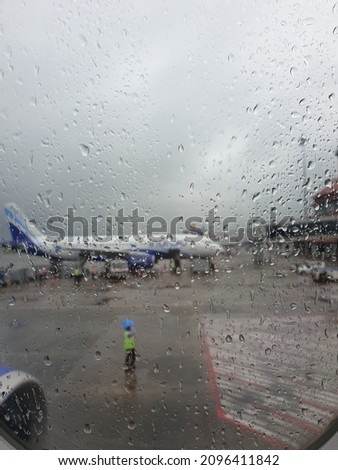Rain drops on flight window and view of another parked flight
