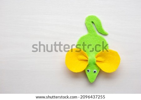 Handmade felt mouse on a light background. Toy mouse made of green and yellow felt