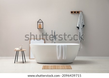 Modern ceramic bathtub near light wall indoors Royalty-Free Stock Photo #2096439715