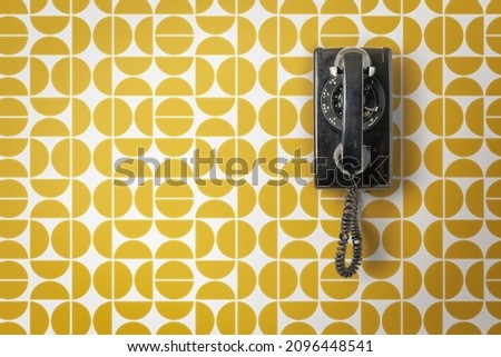 wall telephone hanging on vintage mid century modern wall paper Royalty-Free Stock Photo #2096448541