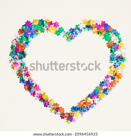 Heart symbol made of flower shaped glitter on white background. Love valentines or woman's day concept. Minimal flat lay.