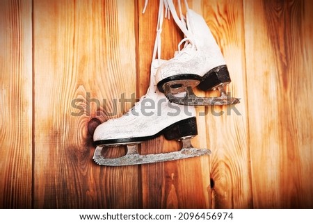 Pair of vintage skates hanging on a wooden background.	