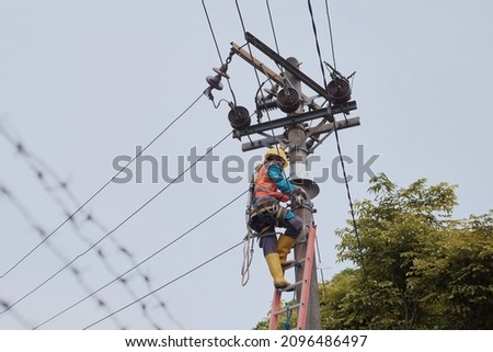 An officer repairs the existing electricity network in Salatiga City. Royalty-Free Stock Photo #2096486497