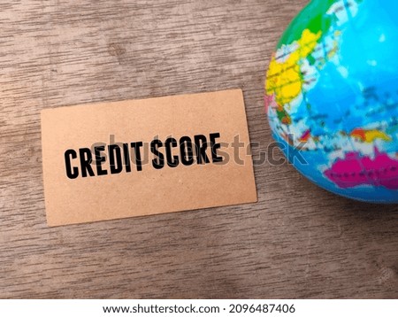 Brown card and blur world globe with text CREDIT SCORE on a wooden background.