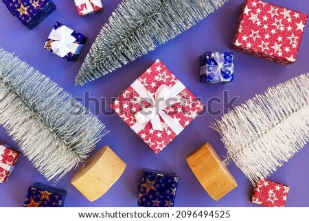 Shiny artificial Christmas trees and gift boxes on purple background, flat lay. Holiday concept for New Year or Christmas.