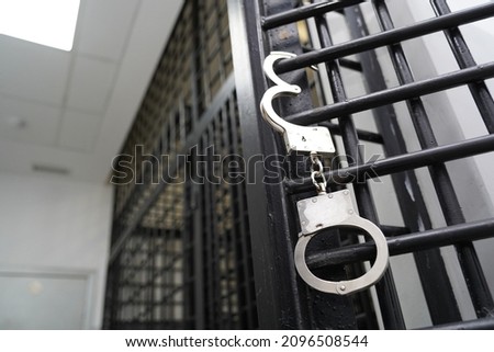 Handcuffs are hanging on the bars of the door of the detention center Royalty-Free Stock Photo #2096508544