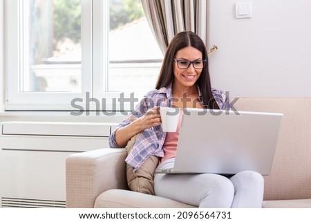Nice beautiful lady with black hair work at the notebook sit down on the sofa at home - check on oline shops for cyber monday sales - technology woman concept for alternative office freelance