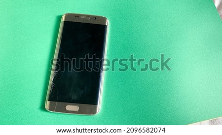 smartphone with broken screen. a smartphone on a green table