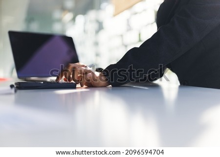 Businessman using a calculator to calculate while working on a laptop in the office. Finance and Accounting Concepts