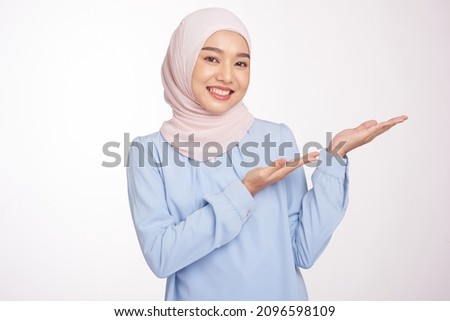 Beautiful hijab girl with hand pointing to empty space for presenting something and presenting product. Royalty-Free Stock Photo #2096598109