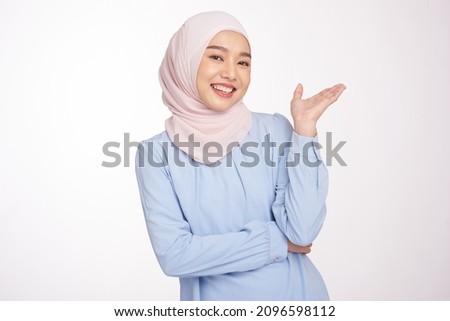 Beautiful asian muslim woman with hands showing and presenting something in the direction of empty space for presenting something and presenting product. Royalty-Free Stock Photo #2096598112